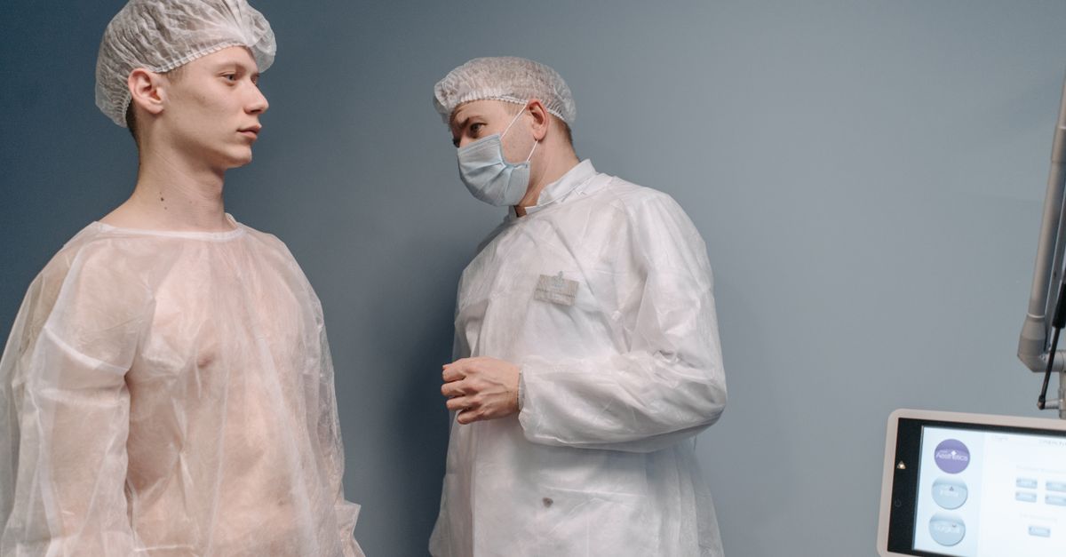A doctor examines a patient in a clinic wearing medical gowns for a mole pathology evaluation.