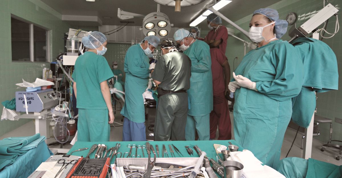 Medical team conducting surgery in a sterile operating room with surgical tools on display.