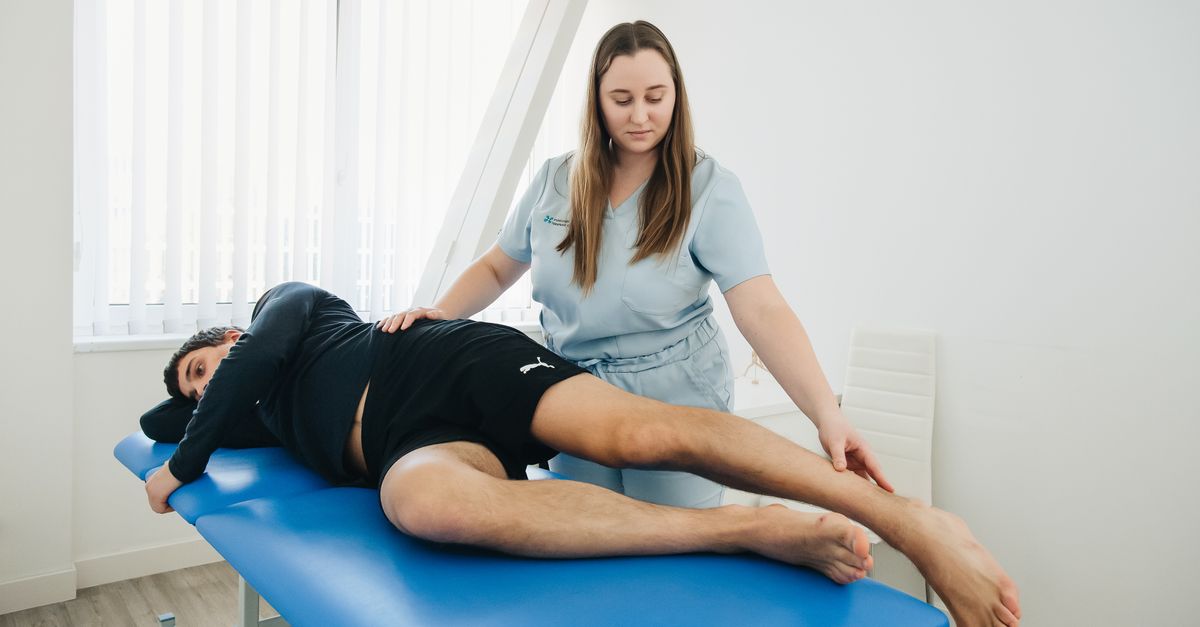 A physiotherapist assists a patient in a rehabilitation session at a Vilnius clinic.