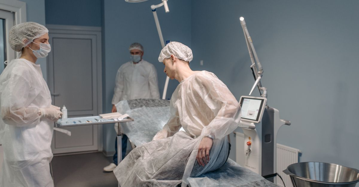 A medical team in sterile gowns prepares for a clinical procedure in a well-equipped room.