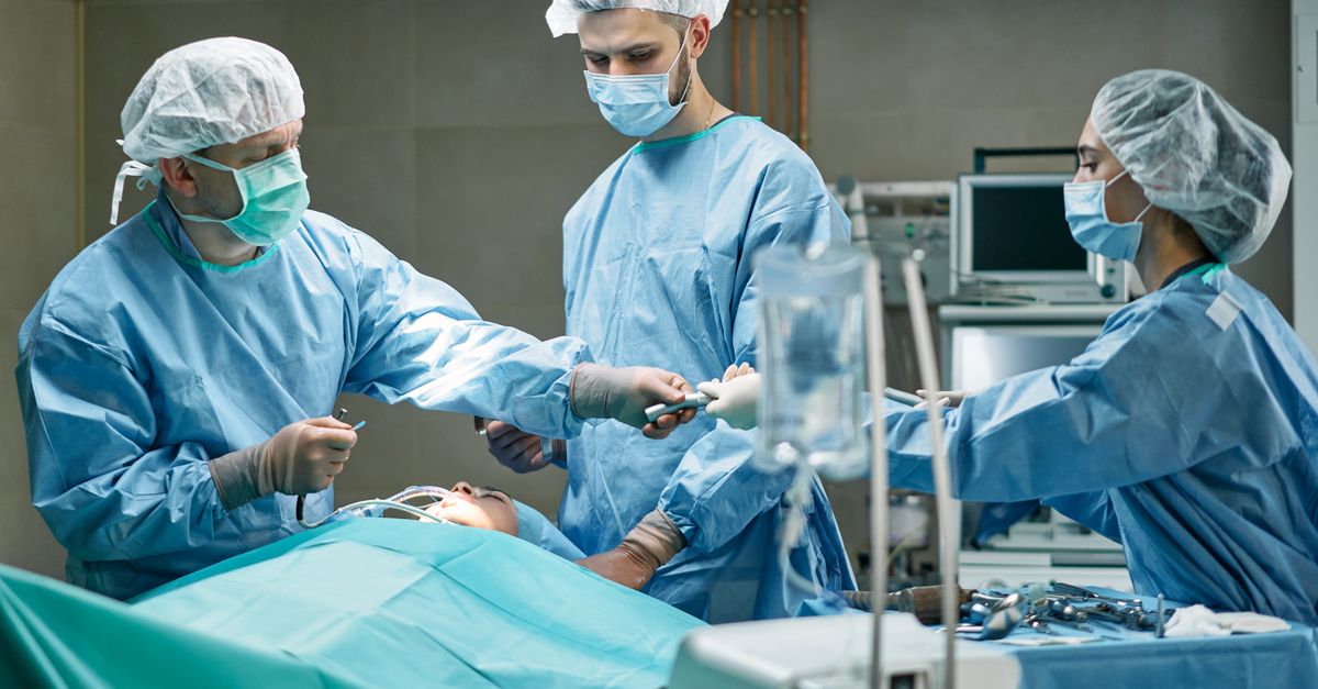 Medical team performing surgery in well-equipped operating room with focus.