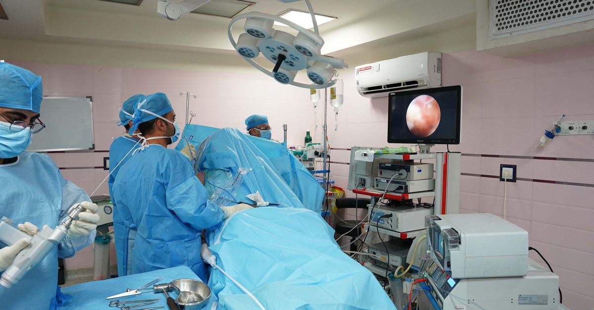 Healthcare professionals in operating room conducting laparoscopic surgery with advanced medical equipment.