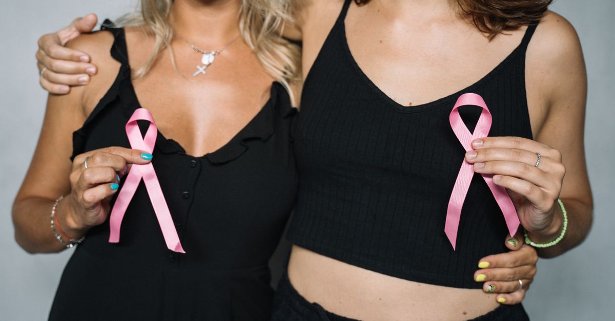 Two women showing support for breast cancer awareness by holding pink ribbons.
