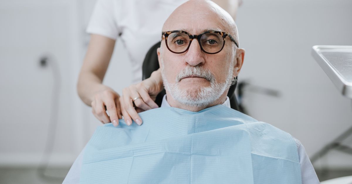 Elderly man in dental chair during appointment, receiving care from dentist.