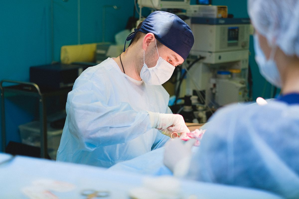 A masked surgeon working with a surgical team in an operating room.